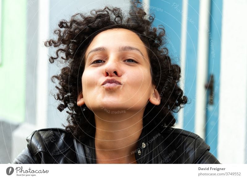 Junge attraktive Frau mit lockigem Haar, die für ein Kamera-Selfie gestikuliert und Küsse schickt. Konzept der städtischen Stadtbewohner. jung Spaß heiter