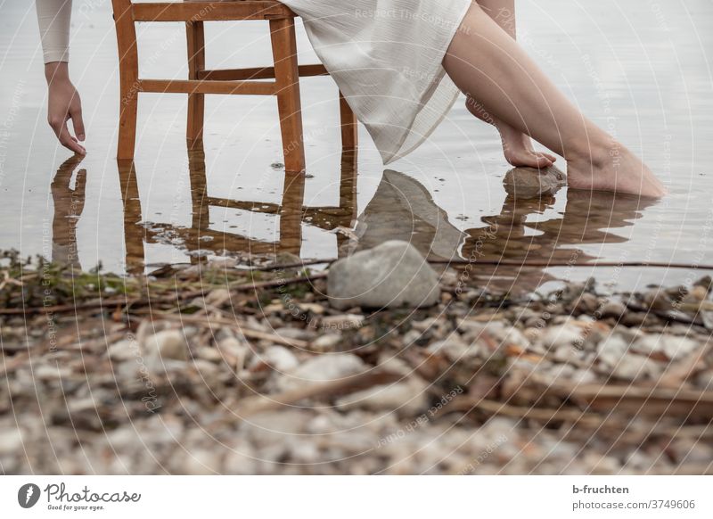 Frau mit weißem Kleid sitzt auf einem Holzstuhl im Wasser Stuhl See Steine ruhig Sommer Reflexion & Spiegelung Erholung Ufer Seeufer Hand Füsse Beine warten