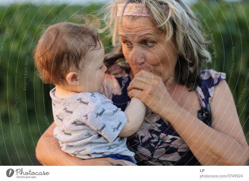 Oma hält kleines Kind und küsst seine Hände Porträt Liebe Liebkosen Wahrheit Vertrauen Lebensfreude Fröhlichkeit Gefühle Kindheit Paar Familie & Verwandtschaft