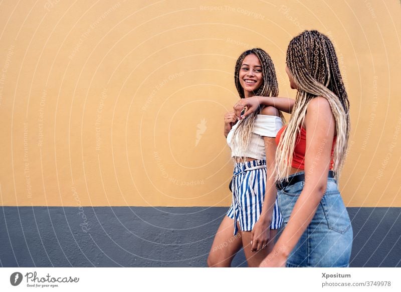 Coole Schwestern haben Spaß Seitenansicht laufen Straße Zopf ethnisch rassisch die sich gegenseitig ansehen Lächeln urban Frauen Porträt zwei Frauen Hintergrund