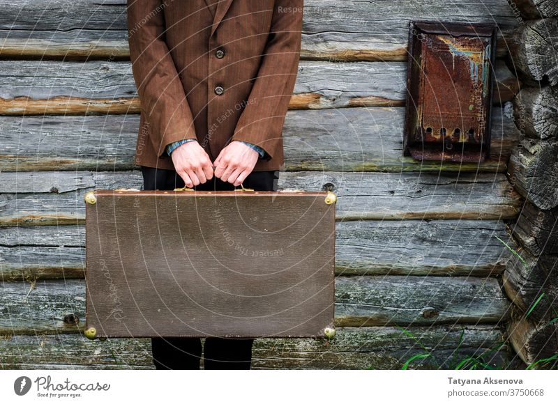Mann Hipster mit altem Retro-Koffer in der Nähe eines alten Landhauses Landschaft cottagecore altehrwürdig Sommer braun Feld grün Jacke retro rustikal reisen