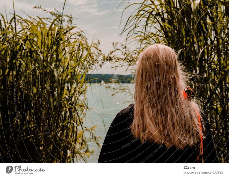 Junge Frau sieht auf den See see gewässer badesee ufer seeufer himmel wolken sträucher baden erholung entspannung urlaub bayern Natur Außenaufnahme Landschaft