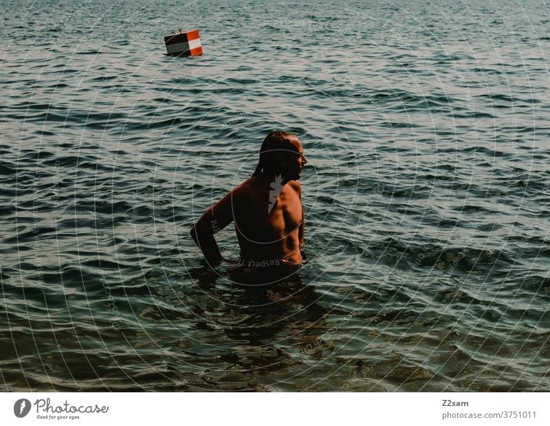 Junger Mann badet im See baden mann sommer sonne schatten licht wasser see gewässer türkis boje Schwimmen & Baden Reflexion & Spiegelung