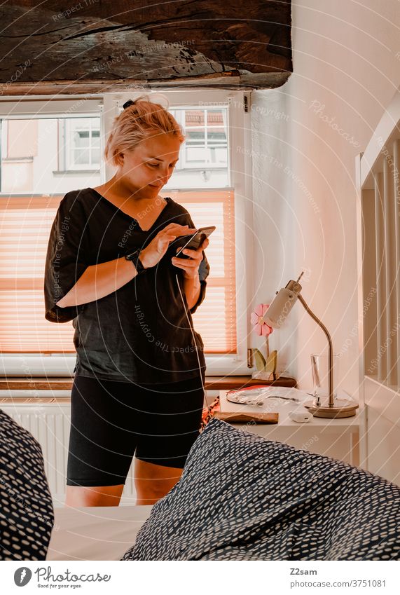 Junge Frau mit Smartphone im Hotelzimmer smartphone kommunikation handy kommunizieren raum schlafzimmer bett frau junge frau blond hübsch entspannt glücklich