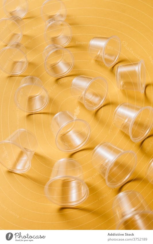 Satz von kleinen Plastikbechern auf gelbem Hintergrund Tasse Kunststoff Einwegartikel Imbissbude durchsichtig Besteck Geschirr Utensil Kulisse Werkzeug