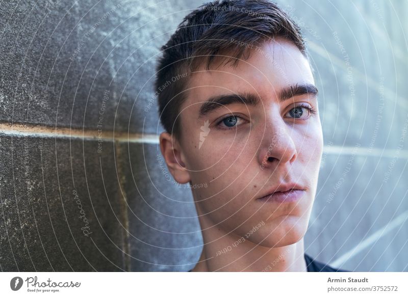 Porträt eines ernsten jungen Mannes, der an einer Wand lehnt Nahaufnahme Lehnen traurig beunruhigt cool Stehen Grunge selbstbewusst Schmutz im Freien Teenager