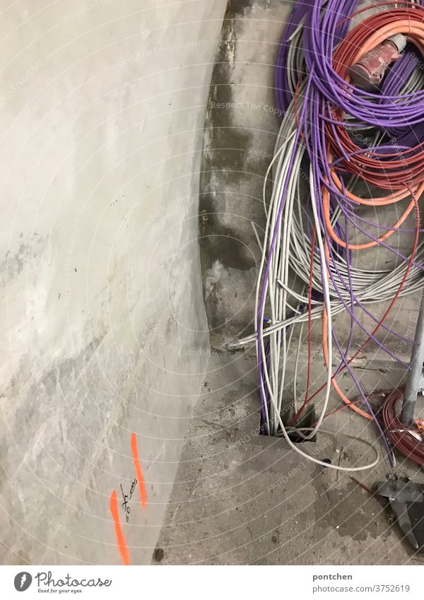 Bunte Kabel hängen aufgerollt durcheinander an einer Betonwand kabelsalat Kabelrolle baustelle Technik & Technologie Kabelsalat Energiewirtschaft
