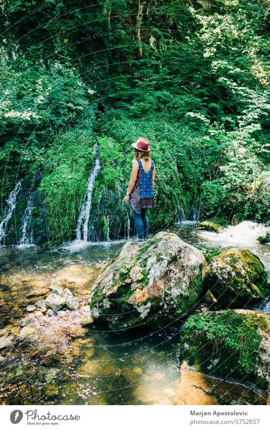 Junge weibliche Naturforscherin geniesst an den Wasserfällen Abenteuer schön Kaskade lässig Kaukasier entdecken Fundstück genießen erkunden Frau fließen