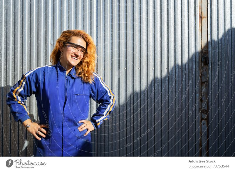 Inhalt weiblicher Arbeiter in Uniform in der Nähe der Fabrik industriell Frau Mitarbeiter Pause Lächeln Brille Pflanze Arbeitsbekleidung Job Metall Wand