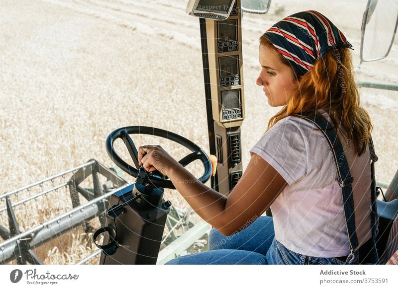 Fokussierte Frau bei der Bedienung einer landwirtschaftlichen Maschine Bauernhof Mähdrescher Ernte arbeiten abholen Saison Feld Ackerbau Weizen ländlich Job