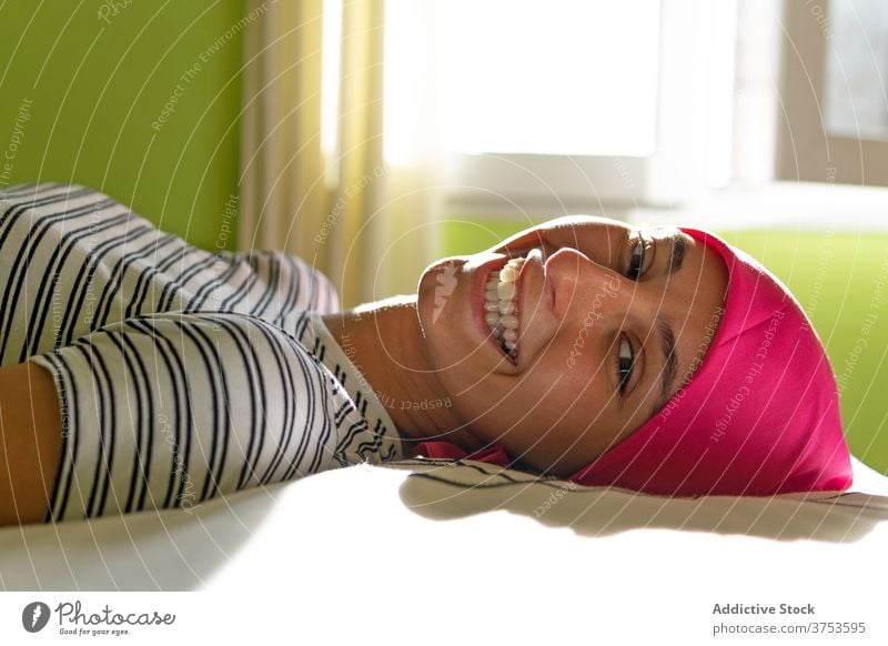 Zufriedene Frau mit Krebs auf dem Bett liegend Hoffnung Lächeln Kopftuch Lügen Überleben Onkologie heimwärts Freude kahl Optimist Krankheit Diagnostik Glaube