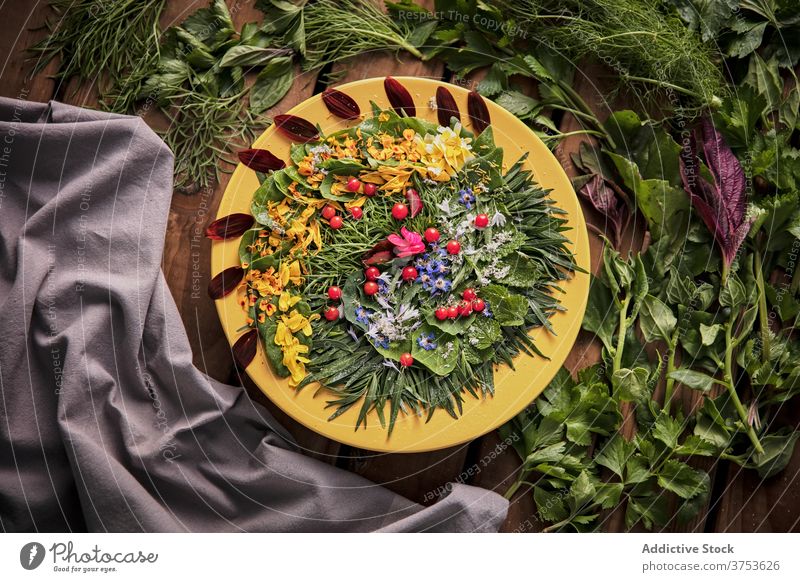 Leckeres Grünzeug mit Blütenblättern auf Teller Blume Zusammensetzung Kraut Ordnung Blütenblatt grün hölzern Tisch reif frisch Natur Sommer Blütezeit Flora