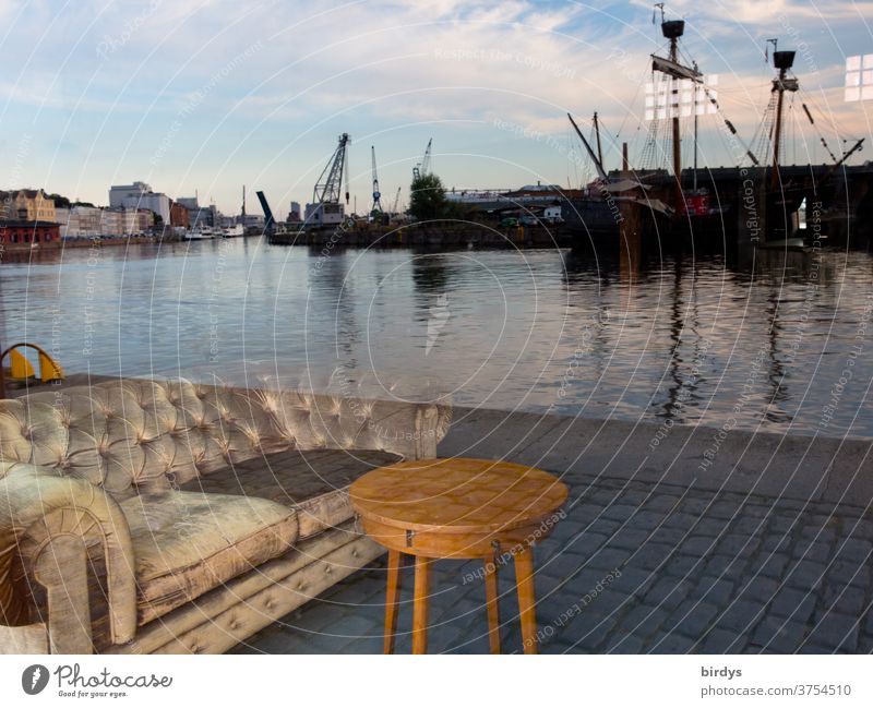 Ein Sofa mit Tisch steht am Kai des Lübecker Hafens. Täuschende Spiegelung in einer Fensterscheibe Reflexion & Spiegelung Schiffe Kräne Hafenanlage Täuschung