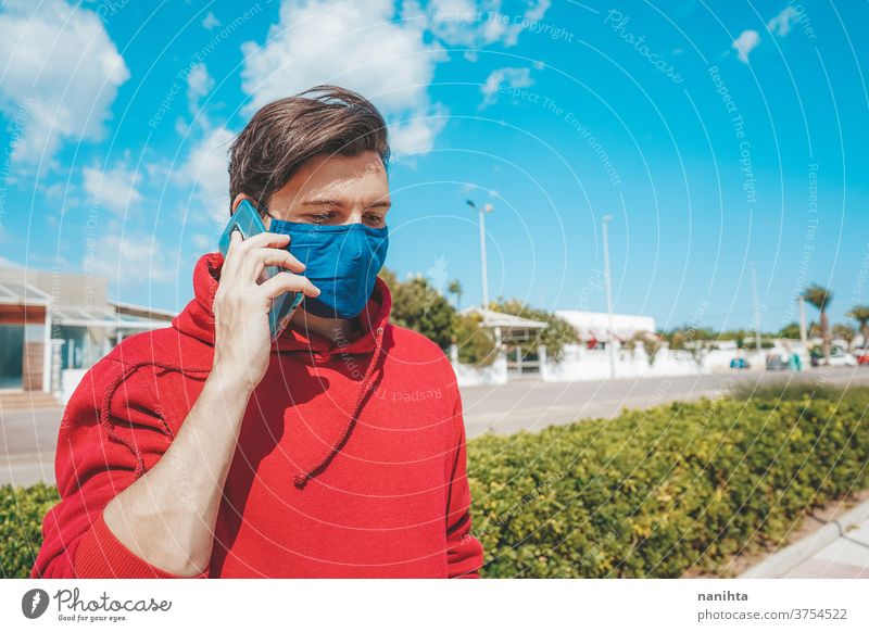 Männer, die sein Smartphone mit Gesichtsmaske in Spanien benutzen COVID neu normal Lifestyle Mundschutz Pandemie Leben Mobile Telefon reden Mitteilungen Mann