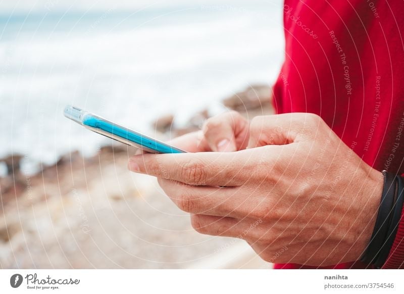 Hände halten ein neues Smartphone Hand klug Telefon Mobile Text Texten Strand Mann männlich jung Jugend Teenager Kapuze im Freien Himmel Technik & Technologie