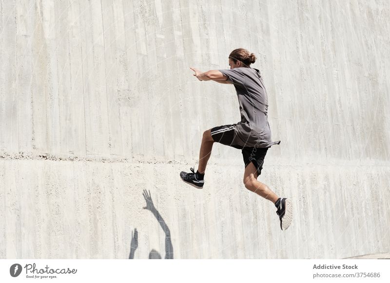 Starker Mann springt auf Gebäudemauer Le Parkour springen Stunt Freestyle Wand Trick urban Großstadt extrem Gefahr männlich Straße Mut jung aktiv gutaussehend
