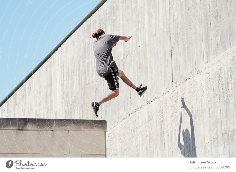 Starker Mann springt auf Gebäudemauer Le Parkour springen Stunt Freestyle Wand Trick urban Großstadt extrem Gefahr männlich Straße Mut jung aktiv gutaussehend
