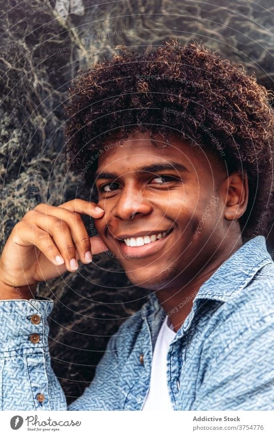 Erfreuter ethnischer Mann schaut in die Kamera Freude Porträt Lächeln gutaussehend charismatisch Großstadt Afro-Look Frisur Vorschein männlich schwarz