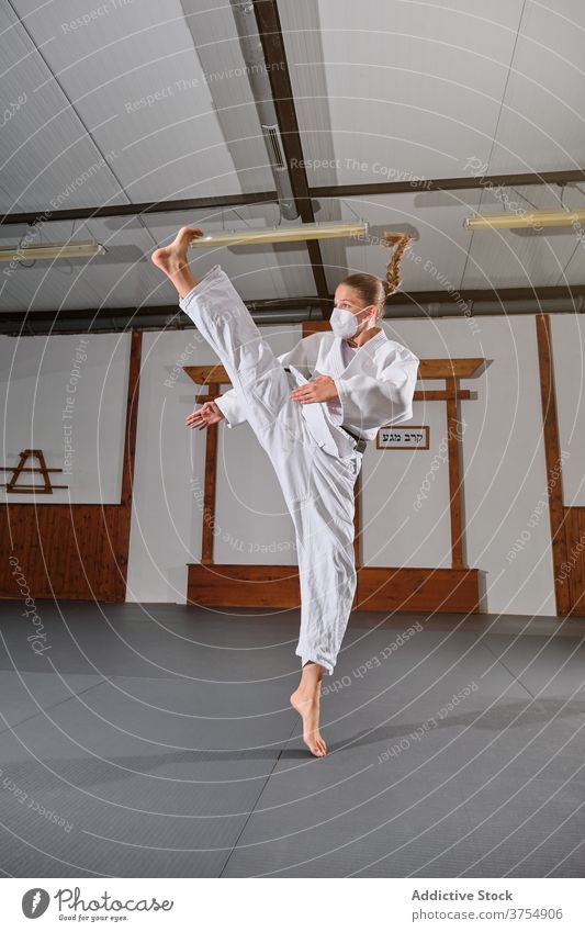 Frau mit weißem Kimono, die in die Luft tritt Körperhaltung Kick Gleichgewicht kampfstark Trainerin Wohlbefinden üben Fähigkeit Stärke Sport Uniform Wellness