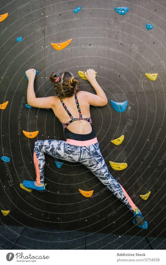 Mutiges Mädchen klettert Wand in der Turnhalle Aufstieg Kind Felsbrocken Fitnessstudio künstlich Felsen Griff Training Gleichgewicht Halt furchtlos üben Übung