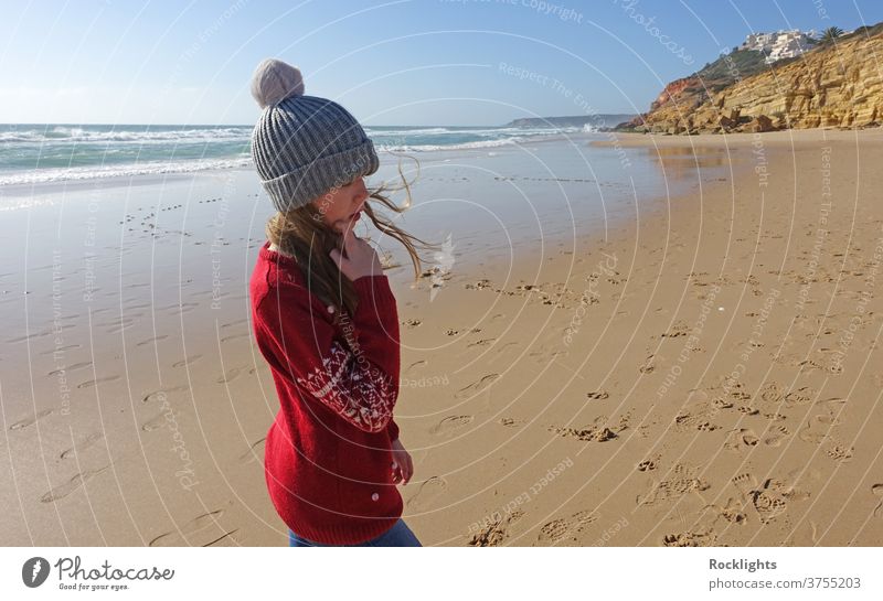 Mädchen mit Pudelmütze am Strand in Portugal im Winter Ufer Kind Spaß Freude Glück Kaukasier Person im Freien reisen Lifestyle Urlaub Wasser schön Algarve