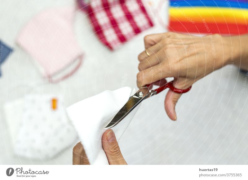 Frauenhände schneiden Gesichtsmasken zum Schutz auf covid-19 Coronavirus Schneiden Schere Mundschutz Hand Gewebe Mode selbstgemacht Stoff Herstellung