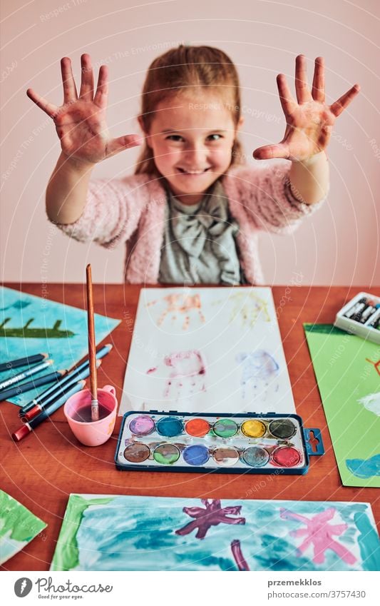 Kleines Mädchen im Vorschulalter mit bemalten bunten Händen Kind Malerei Farbstoff Bildung farbenfroh Kunst heimwärts Papier Kindheit Vorschule Schaffung