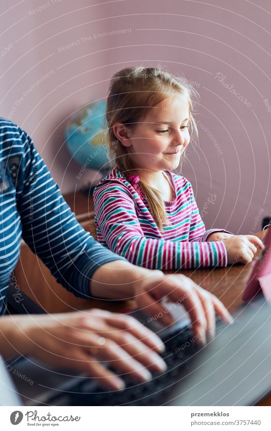 Mutter einer Frau, die während eines Video-Chat-Call-Stream-Online-Kurses auf einem Laptop von zu Hause aus ihren Job aus der Ferne erledigt, während ihre Tochter sich ein Video auf einem Tablet anschaut
