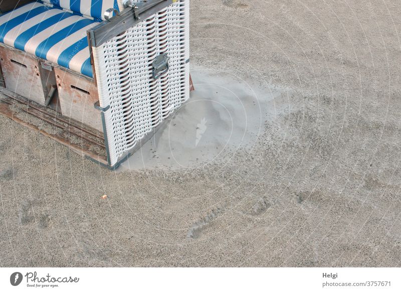 Trockenzone - Teilansicht eines Strandkorbes im Sand nach dem Regen, im Windschatten ist der Sand noch trocken Detailaufnahme nass Insel Nordseeinsel Wangerooge
