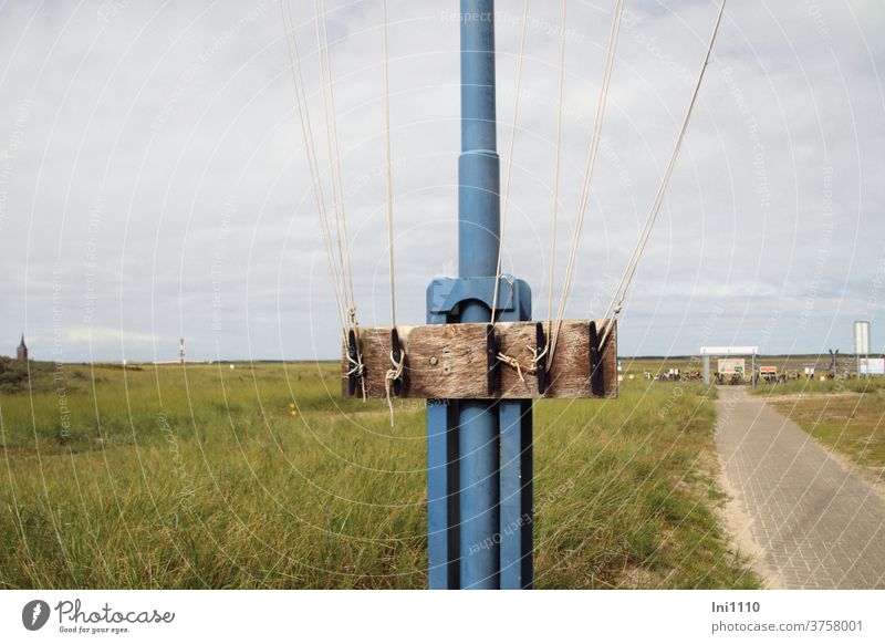 Teilansicht Fahnenmast mit Befestigungsmöglichkeit für Seile Nordsee Insel Wangerooge Hafengelände blau Gras Holz Knoten spannen Nostalgie Sommer schönes Wetter