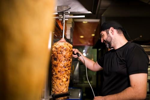 Bärtiger Mann, der in einer Pizzeria Kebab-Fleisch zubereitet. Türkisch Erwachsener Person Menschen Lifestyle attraktiv Männer männlich bärtig Laden Junk Food