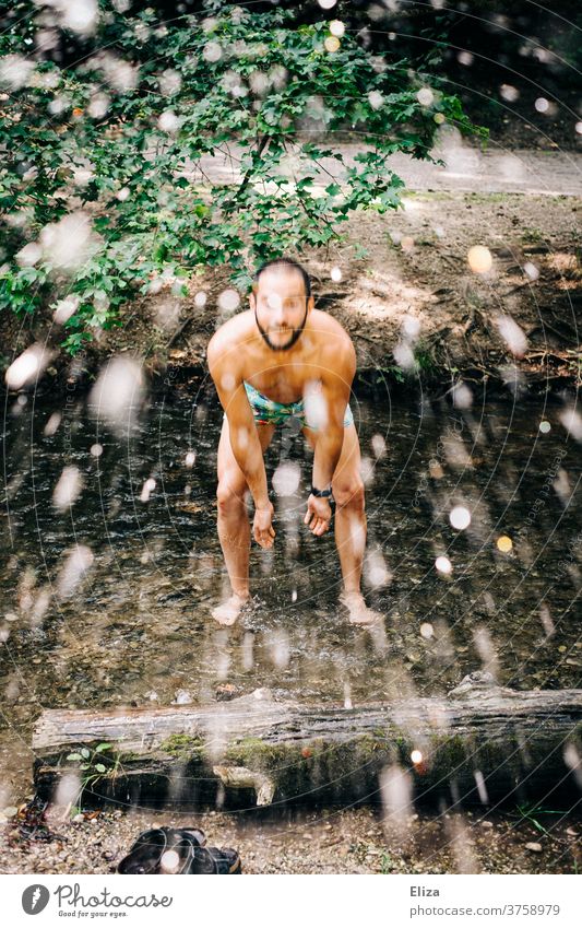 Mann steht in Badehose im Bach und spritzt mit Wasser spritzen Fluss nass Wassertropfen Mensch planschen badehose Spaß Erfrischung Sommer Schwimmen & Baden