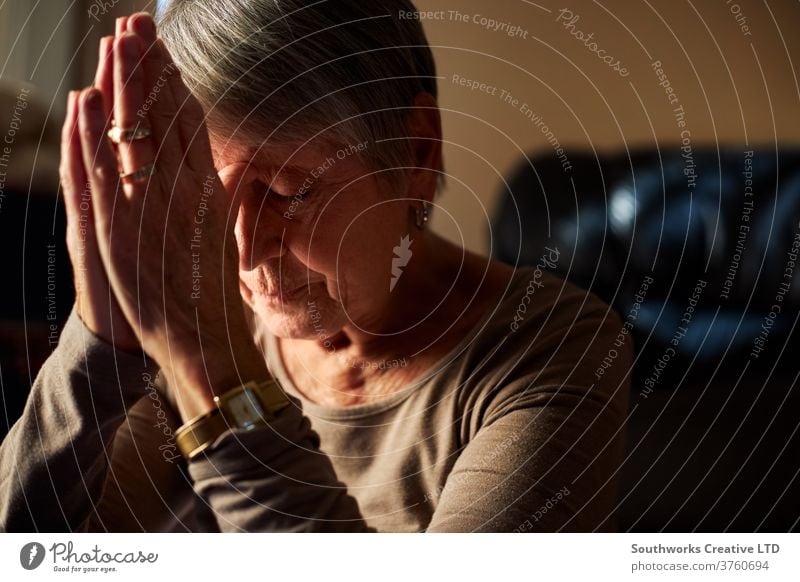 Ältere Frau betet zu Hause heimwärts Sonnenlicht gealtert Windstille im Innenbereich reif Person Erwachsener Pflege älter Senior oap Glaube Gebet Hände