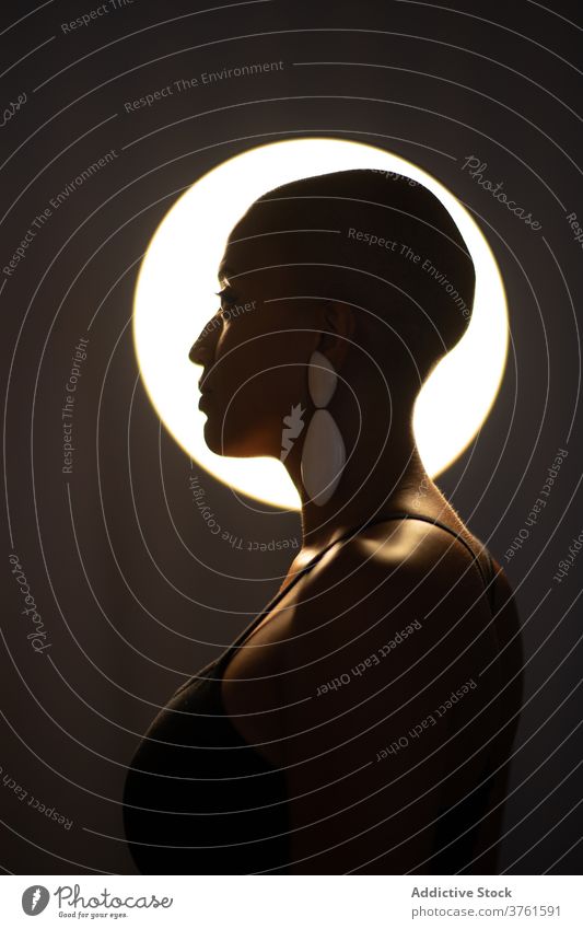 Stilvolle ethnische Frau im dunklen Studio Atelier Lampe leuchten dunkel trendy kahl Frisur Vorschein schwarz Afroamerikaner selbstbewusst ernst Mode charmant