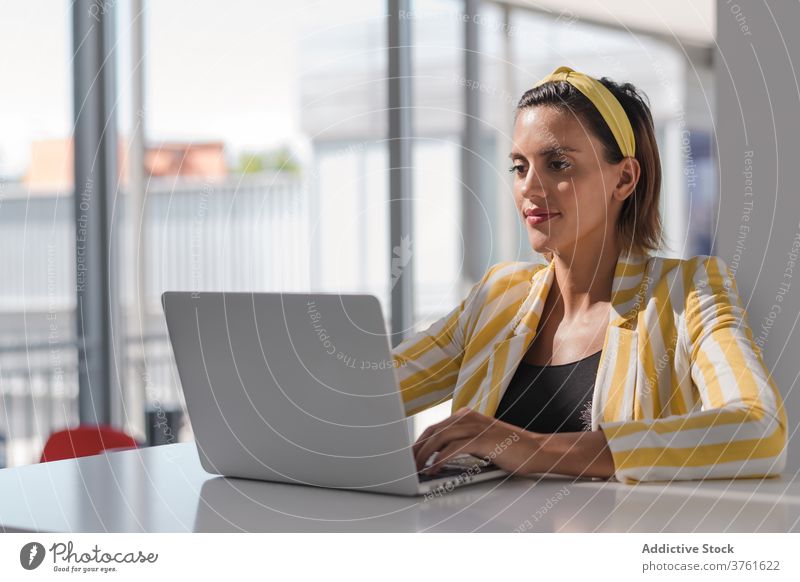 Junge Frau in trendiger Kleidung mit Laptop zu Hause schwanger benutzend Stil trendy Arbeit Arbeitsplatz heimwärts abgelegen freiberuflich positiv beschäftigt