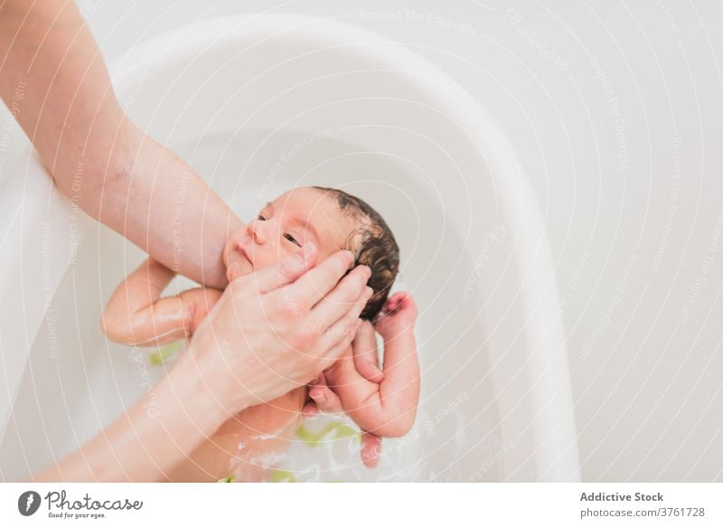 Anonymes Elternteil wäscht Kleinkind im Waschbecken Waschen Baby Becken Wasser weinen heimwärts Pflege Angebot Liebe Kind Säugling neugeboren Sauberkeit Bad