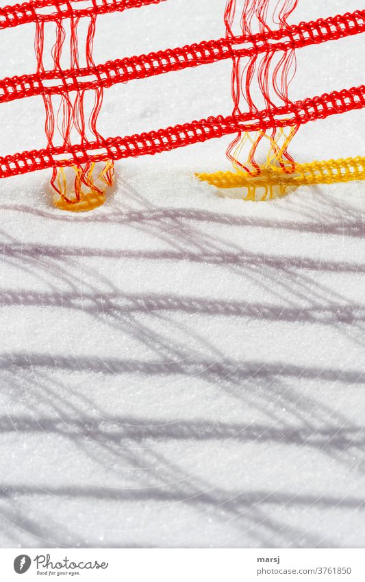 Absperrzaun aus rot gelbem Kunststoff, an der Skipiste schnee geflecht geflochten Absperrung Schattenspiel knallig Strukturen & Formen Detailaufnahme Muster