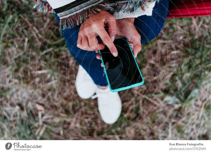 Draufsicht einer Frau, die sich bei Sonnenuntergang in der Hängematte entspannt. Herbstsaison. Camping-Konzept Handy Technik & Technologie Internet App