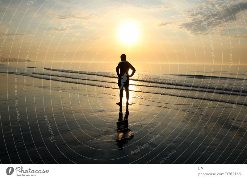 Mann, der am Meeresufer gegen die Sonne steht Führung Anleitung Regie Freiheit Freizeit & Hobby Sonnenuntergangsstrand Sonnenuntergangshimmel