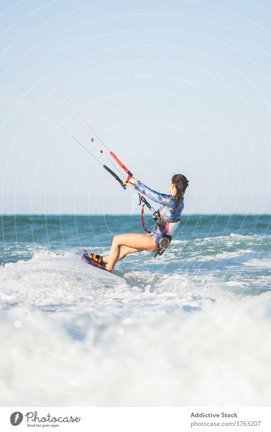 Weiblicher Kite-Surfer reitet auf dem Brett im Meer Milan Brandung Frau Mitfahrgelegenheit winken MEER platschen Sommer professionell Badeanzug passen Erholung