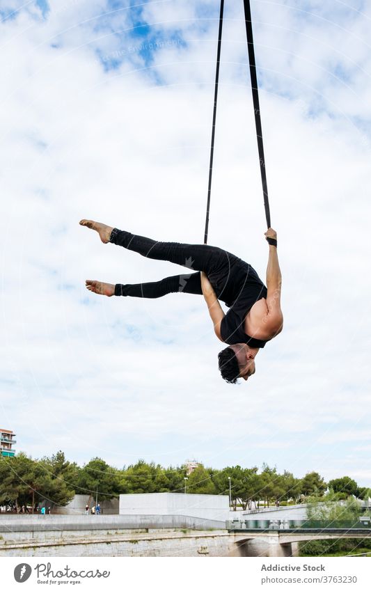 Flexibler Mann trainiert an Traggurten Antenne Gurt Turner Training gymnastisch hängen ausführen beweglich passen Park männlich Übung Energie Athlet Sport