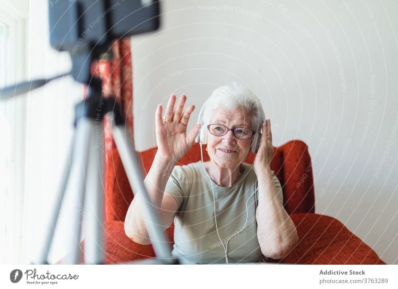Ältere Frau mit Videoanruf mit Kopfhörern Senior zuhören Musik älter Gesang genießen sich[Akk] entspannen heimwärts Freude Armsessel gemütlich sitzen Komfort