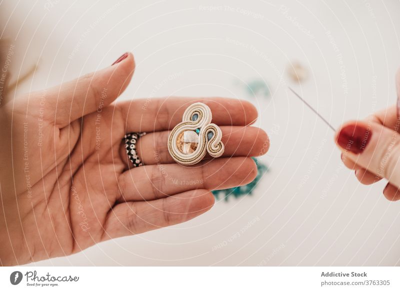 Unerkennbarer Kunsthandwerker bei der Herstellung von Soutache-Ohrringen im Atelier Bijouterie Frau kreieren handgefertigt Werkstatt Prozess Handwerk kreativ