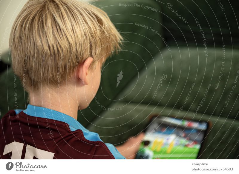 Kleiner Junge spielt mit dem Tablet-Computer Tablet Computer Ipad daddeln Spielen Gaming Kind Bildschirm Bildschirmzeit Erziehung Familie zuhause Fußball game