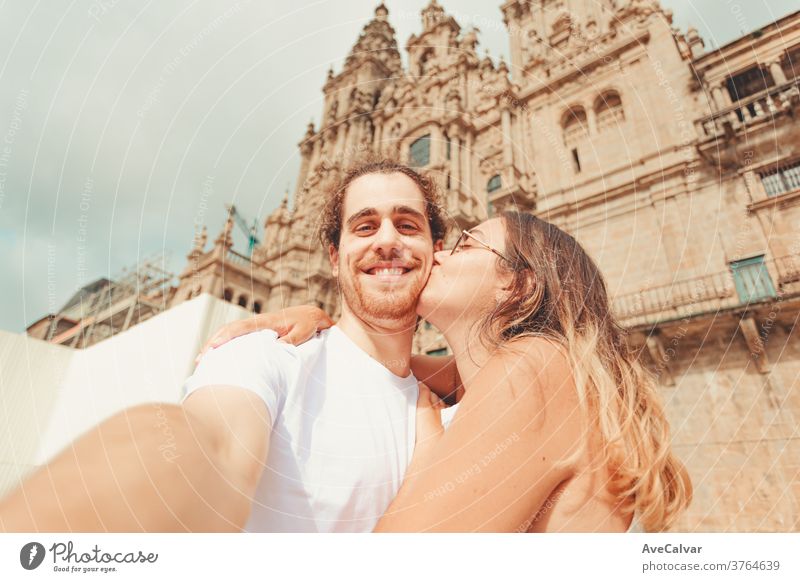 Junger Mann nimmt ein Selfie und lächelt, während seine Freundin ihn küsst Erwachsener Gefühl weiß Spaß Porträt Pose Frau umarmend jung Paar Halt Fröhlichkeit