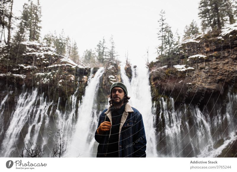 Männlicher Reisender auf Wasserfall in verschneiten bergigen Wald im Winter Tag Mann Schnee fließen Natur Person Landschaft Pool männlich kalt strömen malerisch