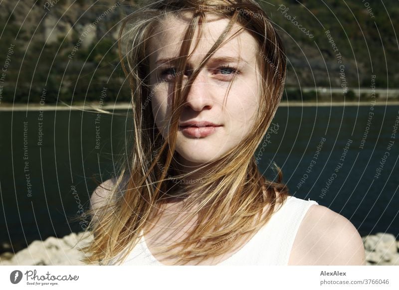 Nahes Portrait einer jungen Frau mit vom Winde verwehten Haaren in weißem Kleid vor Rheinufer junge Frau schlank schön athletisch blond 18-25 Jahre rotblond