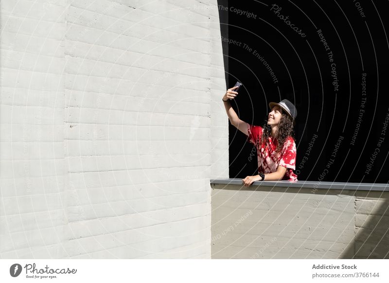 Fröhliche junge Frau mit Selfie auf dem Smartphone Hipster Stil Telefon heiter urban Glück trendy Mobile tausendjährig Hut modern Gebäude Apparatur Gerät
