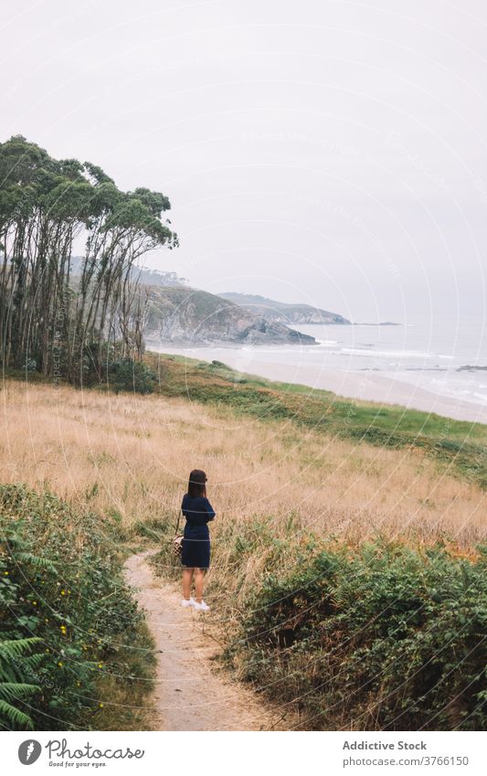 Frau stehend auf Weg am Meer Seeküste einsam bedeckt MEER Küste trist allein Ufer reisen Tourismus Spanien Asturien Frejulfe Strand nachdenken wolkig dumpf