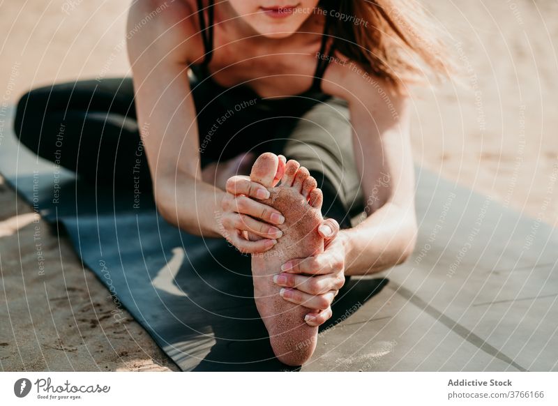 Anonyme Frau macht Yoga in Kopf-zu-Knie-Pose Vorwärtsbeuge beweglich Dehnung Unterlage sich[Akk] entspannen Janu Sirsasana Asana positionieren Strand Gesundheit